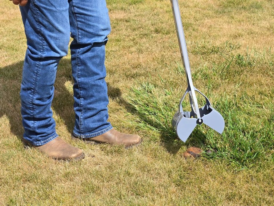 A Dookie Patrol crew member on a lawn with a long-handled pooper scooper